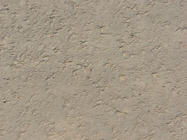Road texture of asphalt covered in light beige dust and slightly rough, irregular surface.